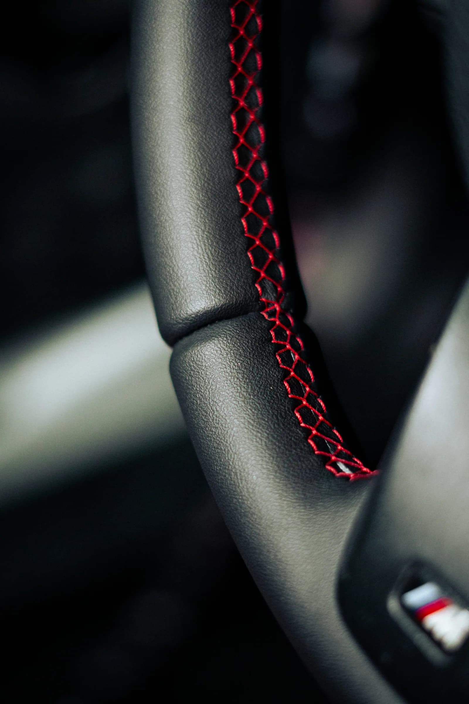 Detalhe da costura vermelha sobre o revestimento preto de um volante BMW